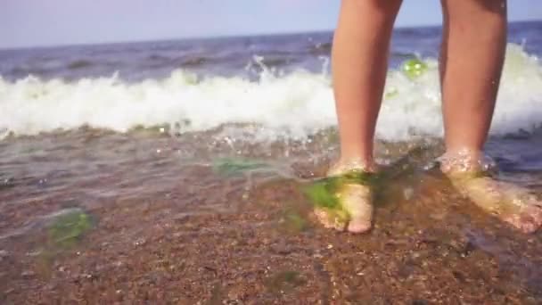 Ralenti : Jambes de fille pieds nus dans le sable sur la plage avec des vagues . — Video