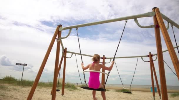 Slow Motion: Beautiful little girl on a swing Baltic Sea in Jurmala, Latvia. — Stock Video