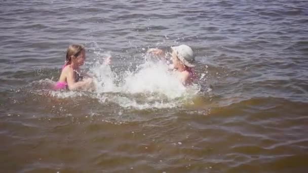 Slowmotion: Två små systrar stänk vatten i Östersjön på varandra på stranden i Jurmala, Lettland. — Stockvideo