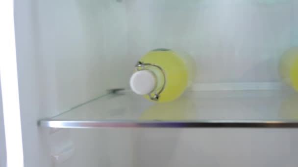 Garrafas com suco de abacaxi amarelo na prateleira no refrigerador — Vídeo de Stock