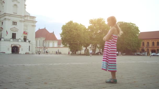 Old Town, Kaunas, Litvanya kalbinde Belediye Meydanı ortasında tribünlerde Kaunas Belediye Binası yakınındaki küçük güzel kız yürüyor. 16. yüzyıl tarihlerinin yapısı. — Stok video