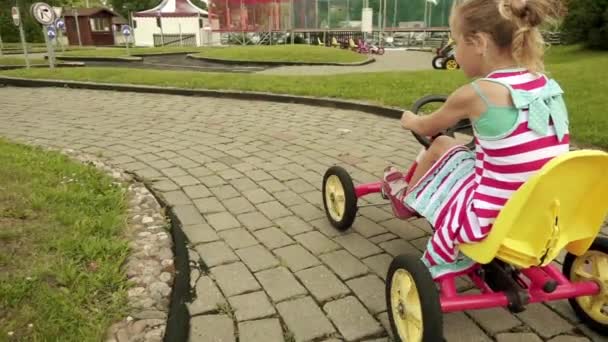 Slow Motion: Mooie meisje rijdt een mechanische go-kart op een eenvoudige Kinder spoor. — Stockvideo