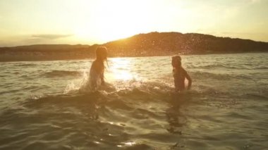 Ağır çekim: İki küçük kız kardeş sıçrama suya başka bir Baltık Denizi kıyısında, Jurmala, Letonya.