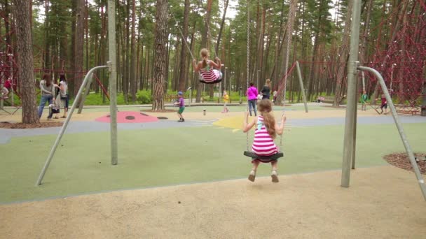 Slow Motion: Dos niñas montan en el columpio en el parque Jurmala, Letonia . — Vídeos de Stock