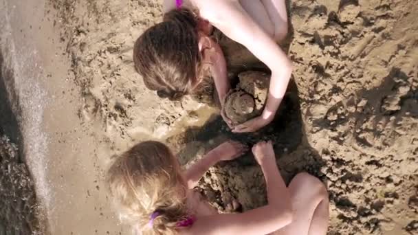 Movimento lento: Duas meninas estão construindo obras de água de areia . — Vídeo de Stock