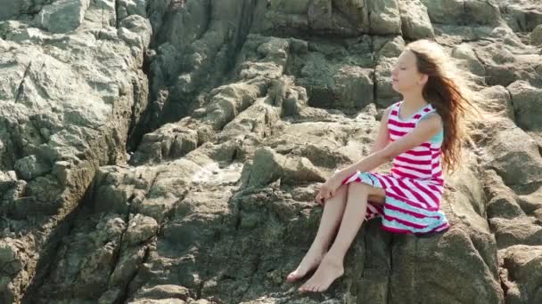 Petite belle fille assise sur le rivage rocheux de la mer Méditerranée . — Video