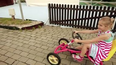 Ağır çekim: Güzel küçük kız mekanik bir go-kart basit bir çocuk yolda rides.