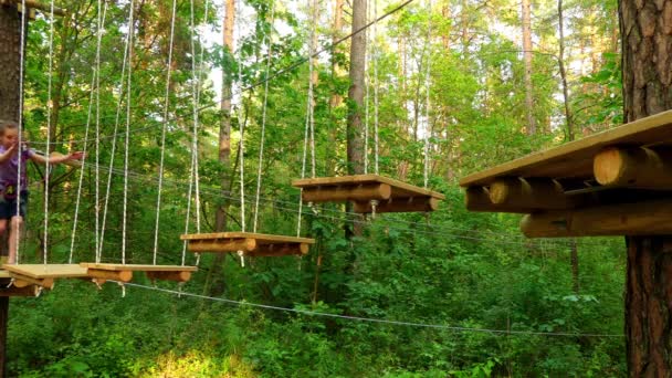 Niña en el parque de aventuras. El parque de aventura es un lugar que puede contener una amplia variedad de elementos, como ejercicios de escalada de cuerdas, pistas de obstáculos y tirolinas. Se destinan a la recreación . — Vídeos de Stock