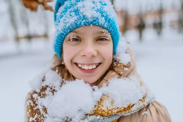 Little smiling girl in blue cap in snow — Stock Photo, Image