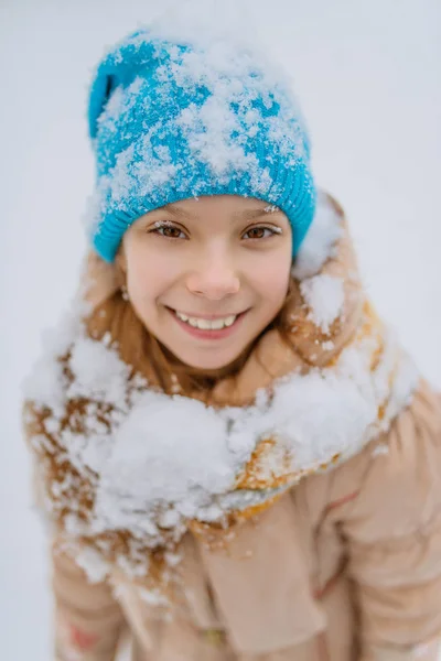 Lilla leende flicka i blå mössa i snö — Stockfoto