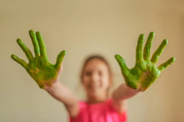 Malá holka ukazuje rukou, které maloval zelené barvy — Stock fotografie