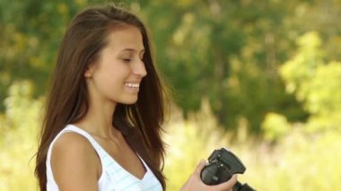 kamera Park yaz yeşil karşı gülümseyen güzel genç kadın portresi.