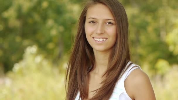 Retrato de la joven hermosa mujer sonriente en el fondo del verde parque de la ciudad de verano . — Vídeos de Stock