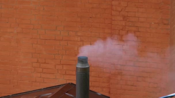 Kouř vychází z kovové trubky na pozadí hnědá cihlová zeď. — Stock video
