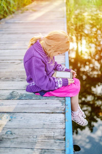 Pequeña chica hermosa leer libros electrónicos — Foto de Stock