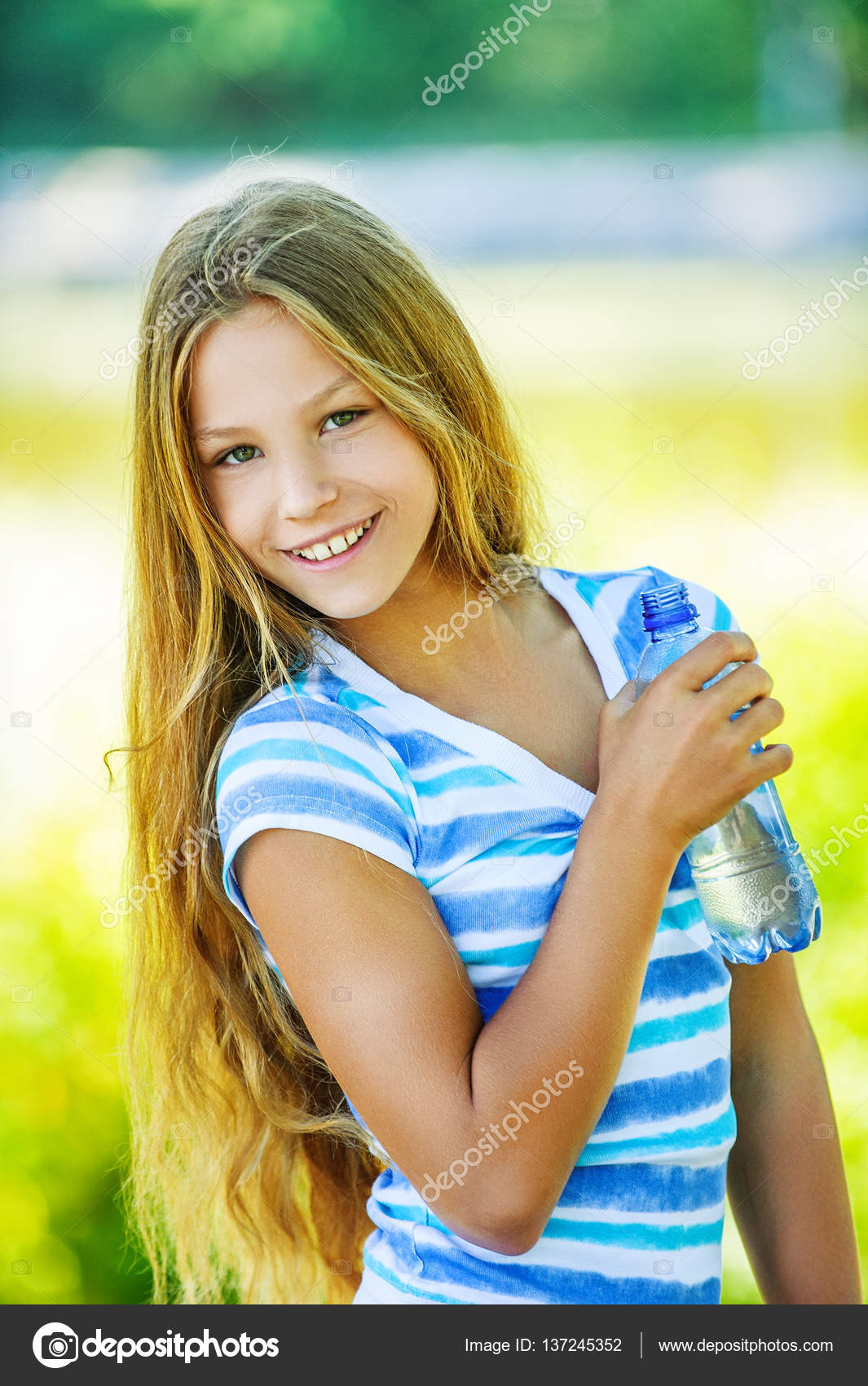 Beautiful teen girl holding bottle of water, smiling and drinking fresh  water Stock Photo