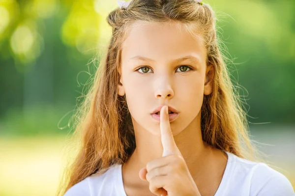 Tienermeisje opgeheven wijsvinger aan haar lippen — Stockfoto