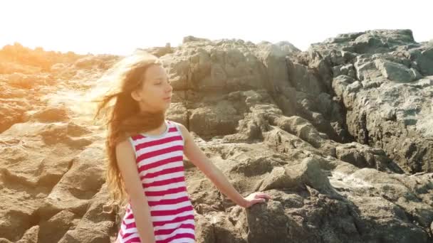 Niña hermosa sentada en la orilla rocosa del mar Mediterráneo . — Vídeos de Stock