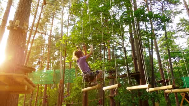 Klein meisje in avonturenpark. Avonturenpark is plaats die grote verscheidenheid van elementen, zoals touwklimmen oefeningen, hindernisbanen en zip-lijnen kan bevatten. Zij bestemd voor recreatie. — Stockvideo