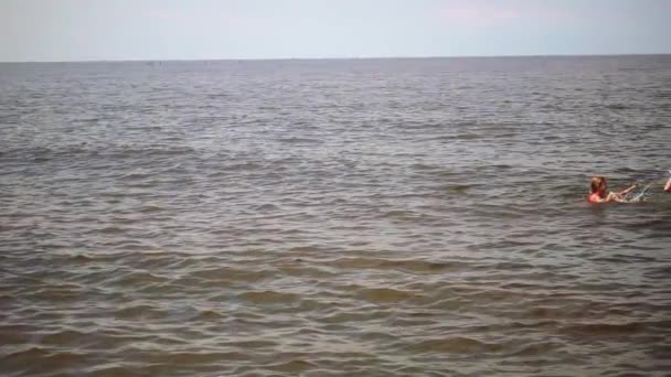 Slow Motion: Dos hermanas pequeñas salpican agua en el Mar Báltico una sobre la otra en las orillas de Jurmala, Letonia . — Vídeos de Stock