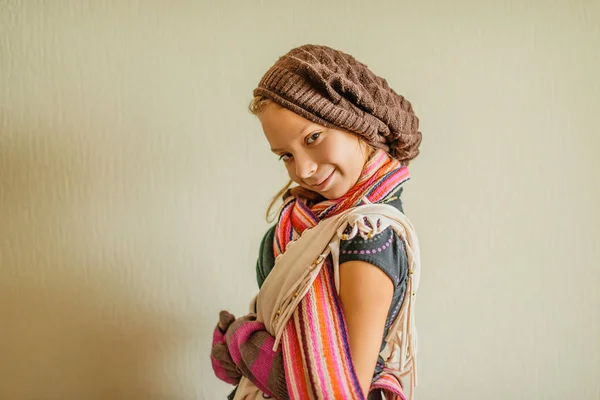 Pequena menina sorridente em um boné e um lenço longo — Fotografia de Stock