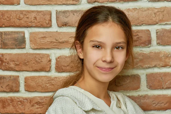 Pequeña hermosa chica sonriente cerca de la pared de ladrillo — Foto de Stock