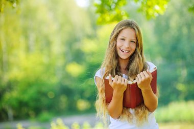 Çok genç kız gülerek kırmızı kitap okur