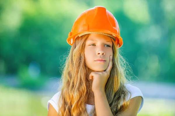 Linda chica joven en un casco de construcción naranja — Foto de Stock