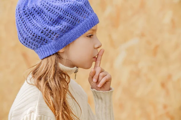 Маленькая девочка в голубой кепке призывает к молчанию — стоковое фото