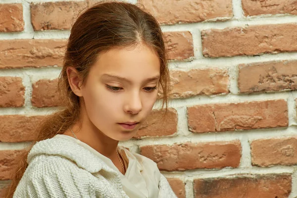 Pequeña chica triste hermosa cerca de la pared de ladrillo —  Fotos de Stock