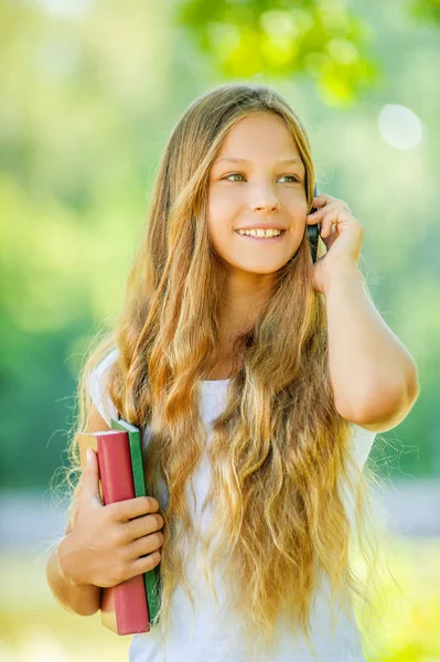 Девочка-студентка с учебниками разговаривает по телефону — стоковое фото