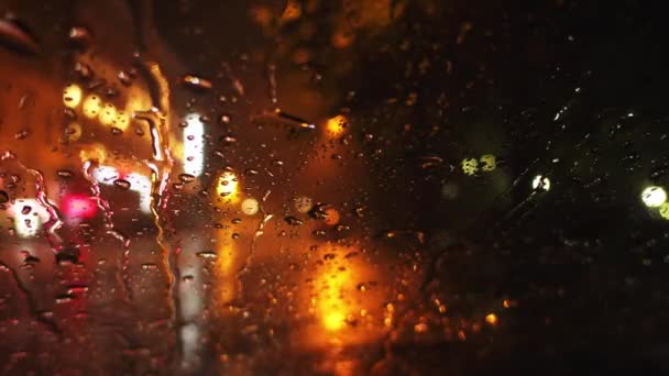 Lluvias fuertes en la calle de la noche en la gran ciudad. Vista a través del parabrisas húmedo del coche en la carretera . — Vídeos de Stock