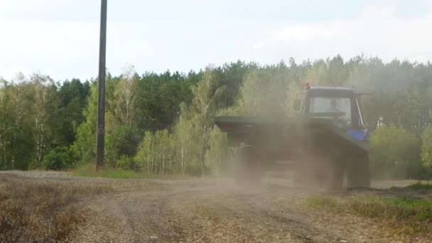 Tractor rides along dirt road, picking up dust behind it. — Stock Video