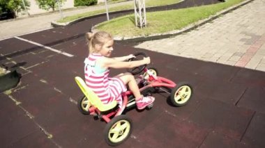 Ağır çekim: Güzel küçük kız mekanik bir go-kart basit bir çocuk yolda rides.
