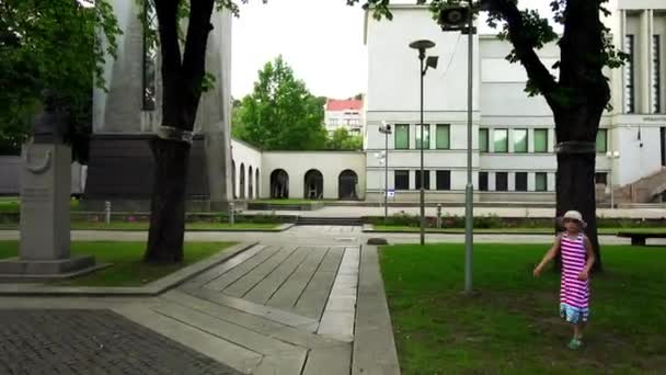 Kleines schönes Mädchen geht in der Nähe des Denkmals für diejenigen, die für die Freiheit und die erlöschende Flamme in Kaunas, Litauen gestorben sind. — Stockvideo