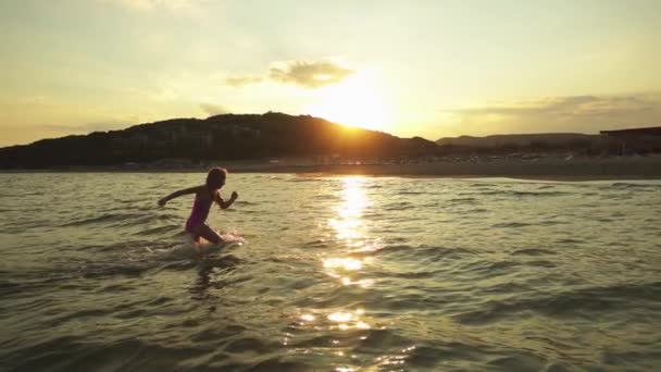 慢动作： 美丽的小女孩扮演在温暖的夏季海里的浪. — 图库视频影像