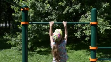 Küçük kız yaz Şehir Parkı içinde yatay çubuğu yukarı çeker.