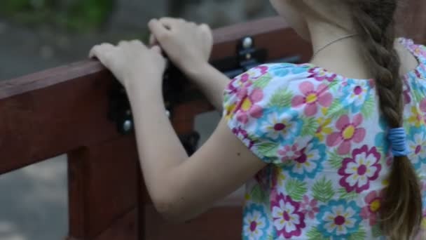 La bambina chiude il bullone sul cancello di legno . — Video Stock