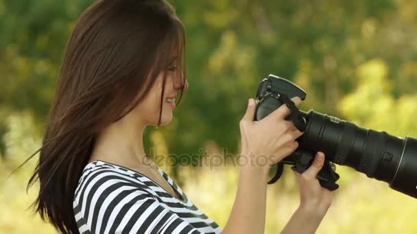 Porträt einer jungen schönen Frau mit der Kamera fotografiert, auf grünem Hintergrund Sommer Natur. — Stockvideo