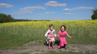 Ağır çekim: İki güzel küçük neşeyle yukarı yaz Şehir Parkı arka plan günbatımı karşı atlama kız kardeş.