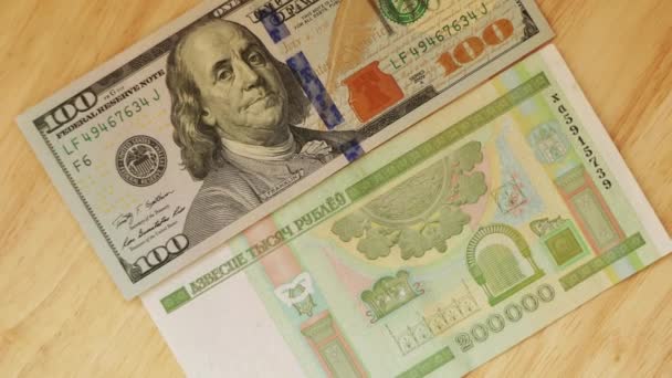 Белорусские рубли номинальной стоимостью двести тысяч лживых и доллар США на деревянном столе . — стоковое видео