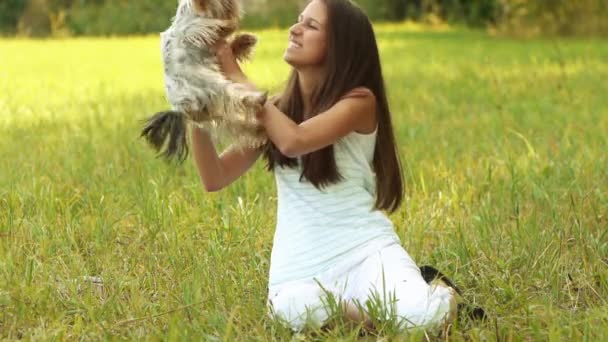 Junge schöne lächelnde Frau mit Yorkshire Terrier, gegen das Grün des Sommerparks. — Stockvideo