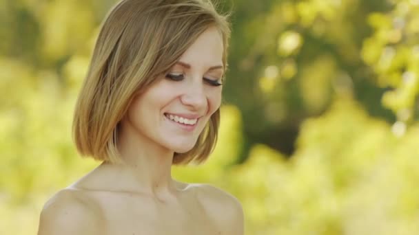 Junge schöne Frau mit nackten Schultern setzt Lippenstift auf die Lippen vor dem Hintergrund des grünen Sommer Stadtpark. — Stockvideo