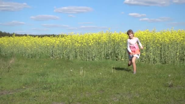 Movimiento lento: Hermosa niña está corriendo felizmente contra el fondo del campo de verano con escofina de floración amarilla . — Vídeo de stock