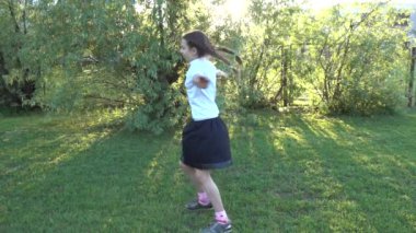 Ağır çekim: güzel küçük kız eğleniyor yaz şehir Park arka plan günbatımı karşı döne döne.