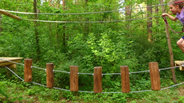 Menina pequena no parque de aventura. Parque de aventura é lugar que pode conter grande variedade de elementos, tais como exercícios de escalada de corda, cursos de obstáculos e tirolesa. Destinados a recreação . — Vídeo de Stock