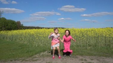 Ağır çekim: İki güzel küçük neşeyle yukarı yaz Şehir Parkı arka plan günbatımı karşı atlama kız kardeş.