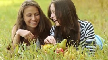 İki güzel genç kadın yeşil çim üzerinde yalan ve olgun üzüm yemek.