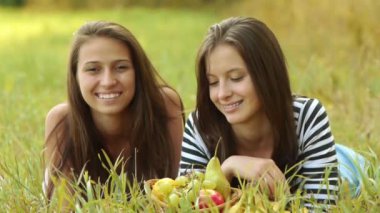 İki güzel genç kadın yeşil çim üzerinde yalan ve olgun üzüm ve armut yiyin.