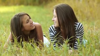 Çim ve konuşmaya üzerinde iki neşeli güzel kızlar genç yalan.